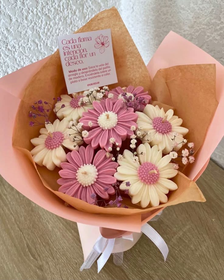 Ramo de velas en forma de margaritas rosas y blancas, con envoltorio y tarjeta.