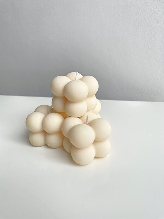 Velas mini burbuja color crema con formas redondeadas sobre una superficie blanca.